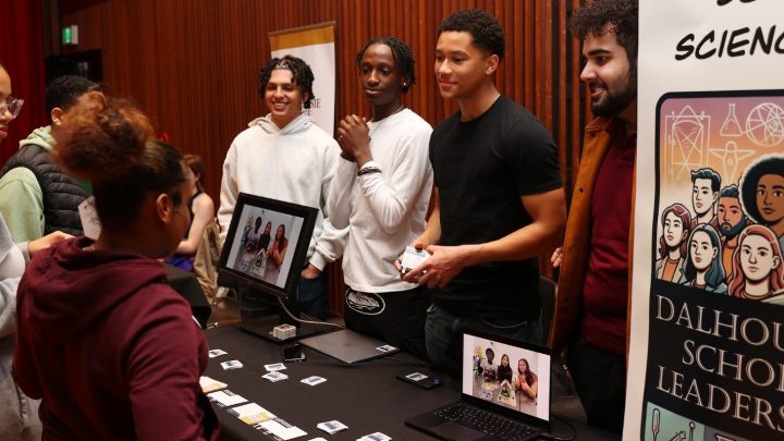 Students engaging with a science outreach booth at a Dalhousie University event, discussing science activities and displays.